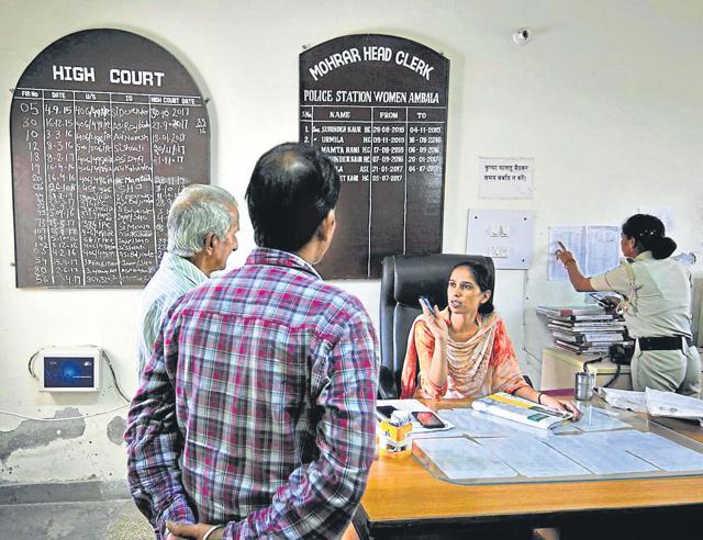 Head constable Simarjit Kaur, the munshi of Ambala’s all­-women police station, attends to a group of men, here to enquire about an FIR. (HT Photo/Ravi Kumar)