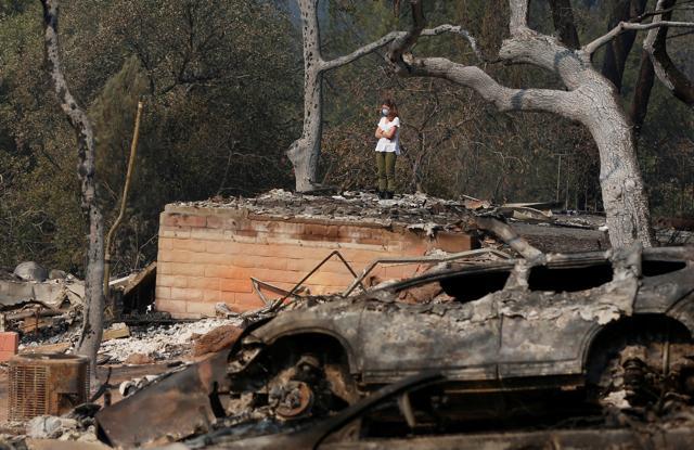 Pamela Garibaldi looks over burned remains of her parents home destroyed by wildfire in Napa, California, US, October 13. (Reuters) Pamela Garibaldi looks over burned remains of her parents home destroyed by wildfire in Napa, California, US, October 13. (Reuters)