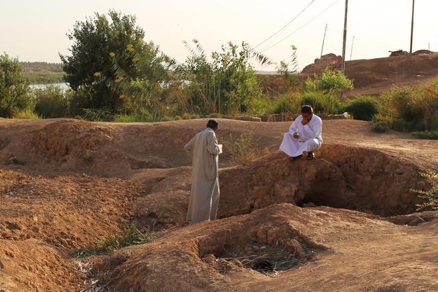 Iraqi men inspect the site of a pit containing the bodies of IS fighters in Dhuluiyah. (AFP)