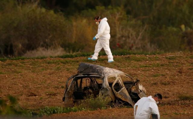 Forensic experts walk in a field after a powerful bomb blew up a car (foreground) and killed investigative journalist Daphne Caruana Galizia. (REUTERS)