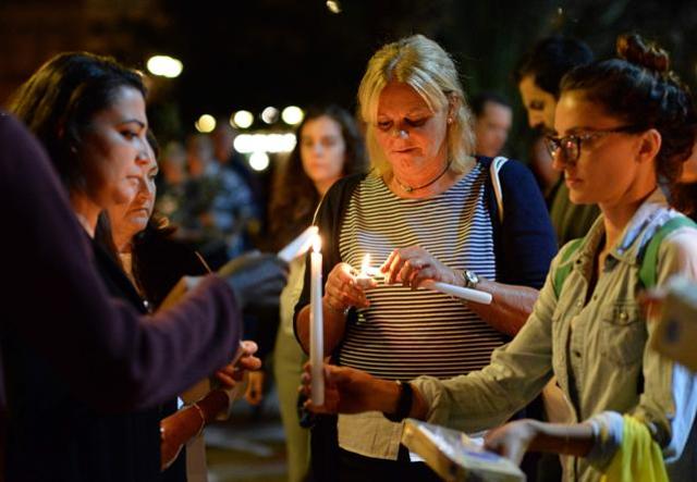 Women light candles during a vigil in Sliema in tribute to late journalist Daphne Caruana Galizia. (AFP)