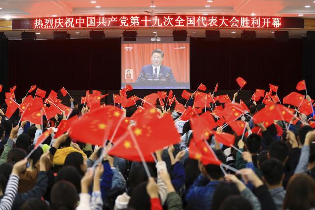Students wave flags as they watch a speech by Chinese President Xi Jinping during the opening ceremony of China's 19th Party Congress in Huaibei in eastern China's Anhui province on October 18. (AP Photo)