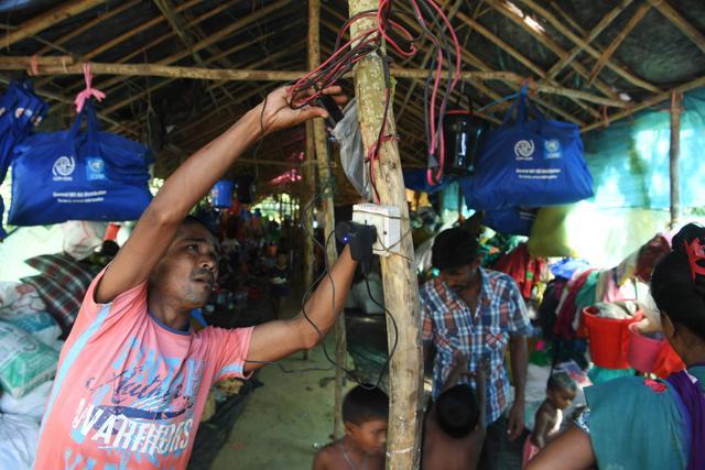 A Hindu refugee from Rakhine state charges his mobile phone at the Kutupalong Hindu refugee camp in the Bangladeshi district of Ukhia on October 15, 2017. The squalid camps in Bangladesh that are now home to nearly 600,000 newly arrived Rohingya have no running water and barely any toilets, but they do have power – thanks to a proliferation of solar panels. (AFP Photo) A Hindu refugee from Rakhine state charges his mobile phone at the Kutupalong Hindu refugee camp in the Bangladeshi district of Ukhia on October 15, 2017. The squalid camps in Bangladesh that are now home to nearly 600,000 newly arrived Rohingya have no running water and barely any toilets, but they do have power – thanks to a proliferation of solar panels. (AFP Photo)