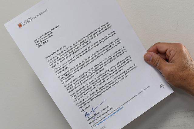 A man holds a copy of the letter sent by Catalan regional government president Carles Puigdemont to Spanish Prime Minister Mariano Rajoy on October 19, 2017 in Madrid. (AFP)