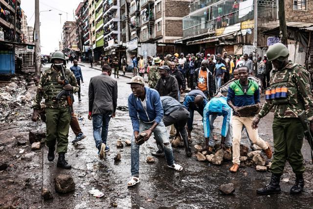 Kenyan security forces and residents clear debris from a street in Mathare, Nairobi on October 26, 2017, as a group of demonstrators attempted to prevent voters to access a polling station for presidential elections. (AFP)