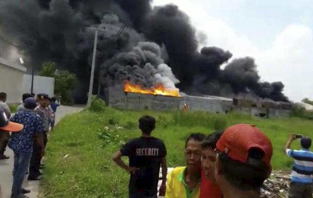 In this image made from video, residents watch as thick black smoke billows from the site of an explosion at a firecracker factory in Tangerang, on the outskirt of Jakarta, Indonesia. (AP) In this image made from video, residents watch as thick black smoke billows from the site of an explosion at a firecracker factory in Tangerang, on the outskirt of Jakarta, Indonesia. (AP)