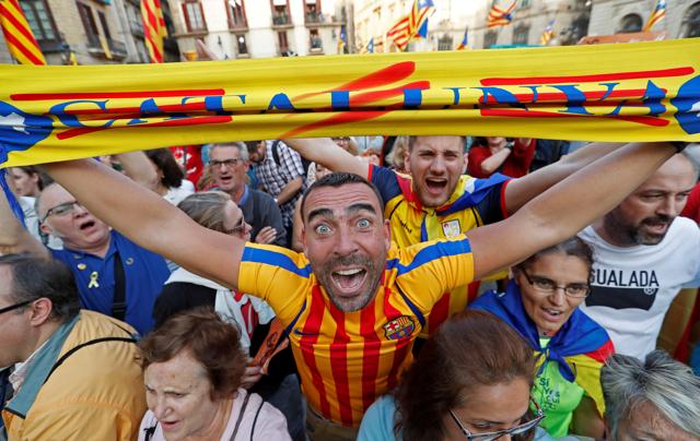 A man displays a scarf featuring an Estelada (Catalan separatist flag) design, as he reacts at Sant Jaume Square after the Catalan regional parliament declares independence from Spain in Barcelona. (REUTERS)