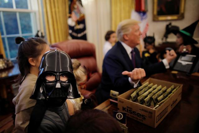 US President Donald Trump gives out Halloween treats to children of members of press and White House staff in the Oval Office of the White House in Washington, DC, US October 27, 2017. (REUTERS) US President Donald Trump gives out Halloween treats to children of members of press and White House staff in the Oval Office of the White House in Washington, DC, US October 27, 2017. (REUTERS)