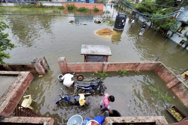 People clear out a flooded courtyard following the onset of the North East Monsoon in Chennai on Tuesday. (PTI Photo) People clear out a flooded courtyard following the onset of the North East Monsoon in Chennai on Tuesday. (PTI Photo)