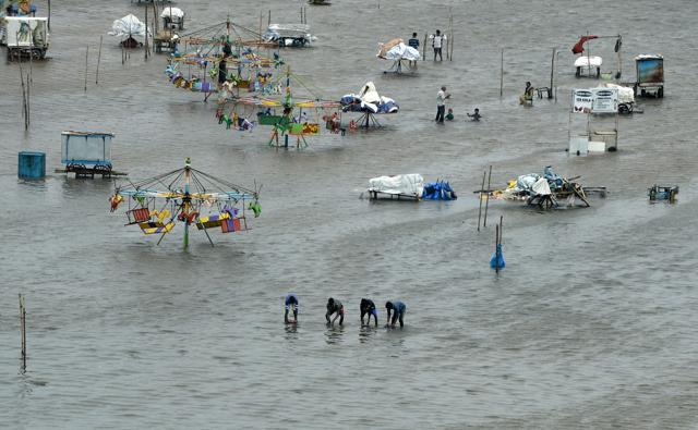 People walk through a flooded area of Marina Beach on the Bay of Bengal coast after heavy rains in Chennai on November 3, 2017. (AFP) People walk through a flooded area of Marina Beach on the Bay of Bengal coast after heavy rains in Chennai on November 3, 2017. (AFP)