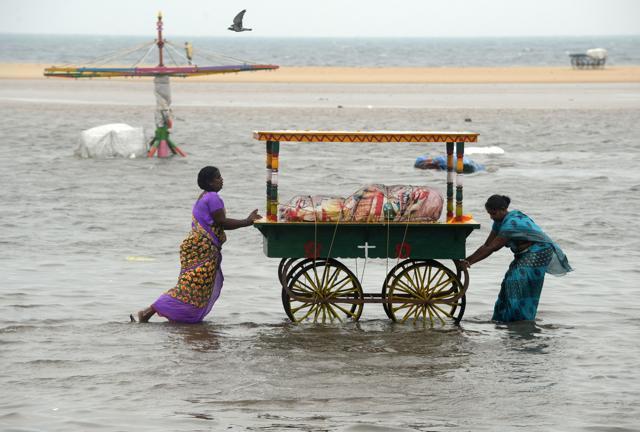 Two women push a food cart through flood waters at Marina Beach on the Bay of Bengal coast, Chennai. (AFP) Two women push a food cart through flood waters at Marina Beach on the Bay of Bengal coast, Chennai. (AFP)