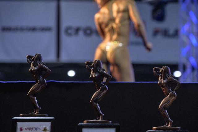 A female bodybuilder works her routine on stage in front of the judges in the hope of winning one of the trophies (foreground) given to the top 5 contestants. (AFP) A female bodybuilder works her routine on stage in front of the judges in the hope of winning one of the trophies (foreground) given to the top 5 contestants. (AFP)