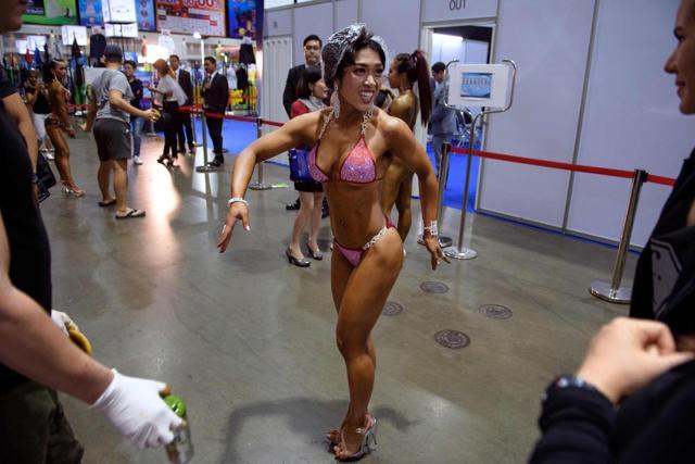 A female bodybuilder practices her moves as she wears a shower cap to protect her hair from a tanning product applied to her body before taking the stage to perform her routine at a local bodybuilding competition. (AFP) A female bodybuilder practices her moves as she wears a shower cap to protect her hair from a tanning product applied to her body before taking the stage to perform her routine at a local bodybuilding competition. (AFP)