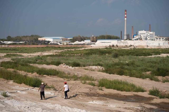 Wang Baoqin and a fellow member (L) of the "Senior Citizen Environmental Protection Team" walk on the farmland that was polluted by the Qihua chemical plant (R) in Yushutun on August 21. (AFP Photo) Wang Baoqin and a fellow member (L) of the "Senior Citizen Environmental Protection Team" walk on the farmland that was polluted by the Qihua chemical plant (R) in Yushutun on August 21. (AFP Photo)