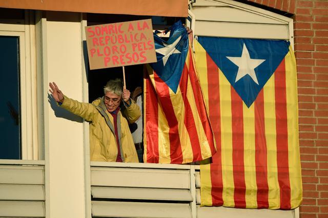 A woman holds a placard reading "I smile at the republic and cry for the prisoners" from a balcony where Catalan pro-independence Estelada flags hand during a demonstration in Barcelona on November 11, 2017 calling for the release of jailed separatist leaders. (AFP)