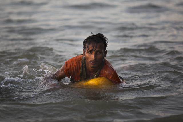 In this Nov. 4, 2017, photo, Rohingya Muslim Abdul Karim, 19, uses a yellow plastic drum as a floatation device as he swims the Naf river while crossing the Myanmar-Bangladesh border in Shah Porir Dwip, Bangladesh. (AP) In this Nov. 4, 2017, photo, Rohingya Muslim Abdul Karim, 19, uses a yellow plastic drum as a floatation device as he swims the Naf river while crossing the Myanmar-Bangladesh border in Shah Porir Dwip, Bangladesh. (AP)