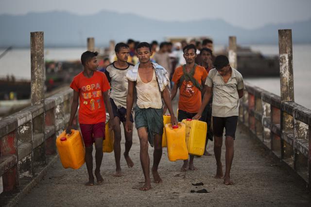 In this Nov. 4, 2017, photo, Rohingya Muslims carrying yellow plastic drums they used as flotation devices walk down the Shah Porir Dwip dock after reaching Bangladesh. (AP) In this Nov. 4, 2017, photo, Rohingya Muslims carrying yellow plastic drums they used as flotation devices walk down the Shah Porir Dwip dock after reaching Bangladesh. (AP)