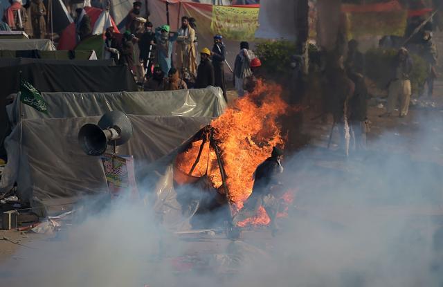 A Pakistani protester from the Tehreek-i-Labaik Yah Rasool Allah Pakistan (TLYRAP) religious group runs past a burning tent during a clash with police in Islamabad on November 25, 2017. (AFP Photo) A Pakistani protester from the Tehreek-i-Labaik Yah Rasool Allah Pakistan (TLYRAP) religious group runs past a burning tent during a clash with police in Islamabad on November 25, 2017. (AFP Photo)