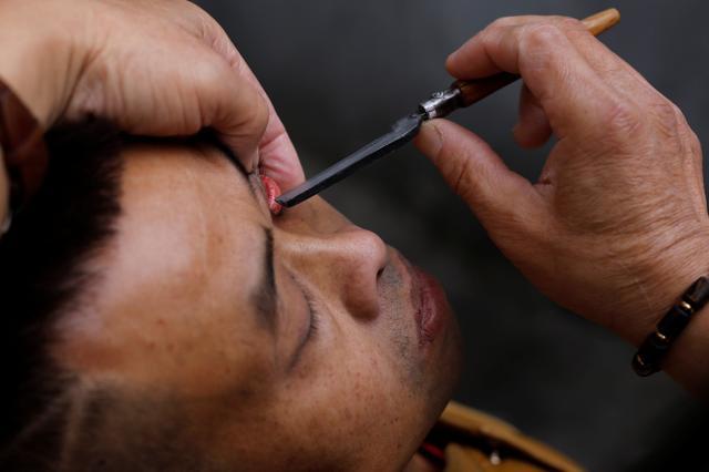 While customers insisted their eyes felt better after a shave, onlookers cringed at the sight of Xiong wielding his razor. (Reuters)