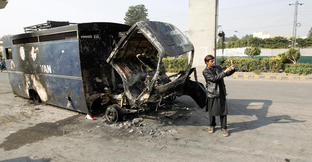 A passerby takes a selfie in front of a police prison van destroyed during clashes with police near the Faizabad junction in Islamabad, Pakistan. (Reuters) A passerby takes a selfie in front of a police prison van destroyed during clashes with police near the Faizabad junction in Islamabad, Pakistan. (Reuters)