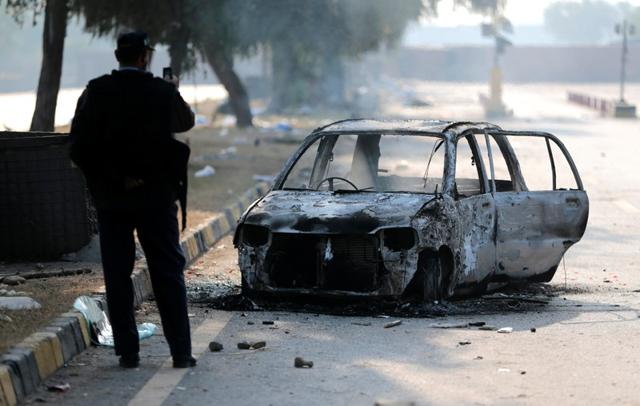 A policeman takes a picture of a car burned during clashes near the Faizabad junction. (Reuters) A policeman takes a picture of a car burned during clashes near the Faizabad junction. (Reuters)