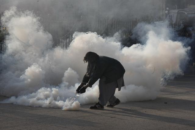 A protester pours water on a tear gas shell fired by police during a clash in Islamabad. (AP Photo) A protester pours water on a tear gas shell fired by police during a clash in Islamabad. (AP Photo)