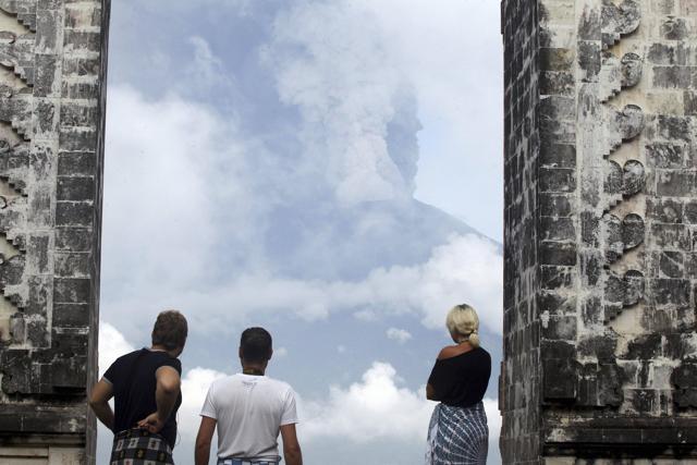 Tourists watch the Mount Agung volcano erupting as they visit a temple in Karangasem, Indonesia, Monday, Nov. 27, 2017. (AP) Tourists watch the Mount Agung volcano erupting as they visit a temple in Karangasem, Indonesia, Monday, Nov. 27, 2017. (AP)