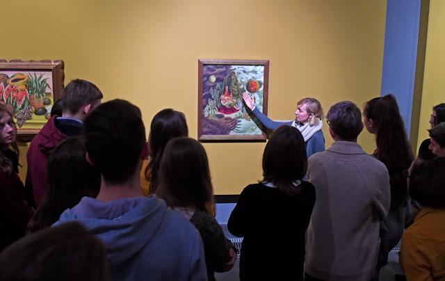 A group of visitors listen to explanations in front of a painting displayed during the exhibition. (AFP)