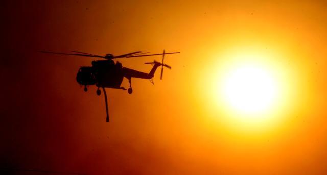 A firefighting helicopter passes by the smoke covered sun during the early-morning Creek Fire. (Reuters)