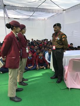 Two second year students from the Mai Bhago Armed Forces Preparatory Institute for Girls interacting with Naib Subedar Sanjay Kumar at the Military Literature Festival in Chandigarh on Saturday. (Yojana Yadav/HT)