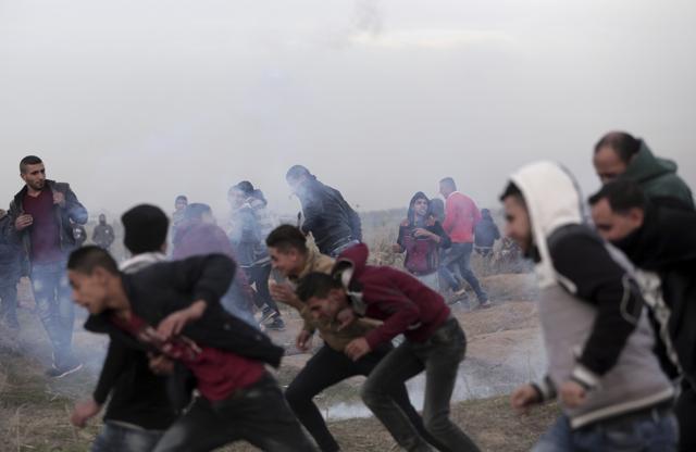Palestinian protesters run for cover from teargas fired by Israeli troops during clashes on the Israeli border with Gaza, Sunday, Dec. 10, 2017. (AP) Palestinian protesters run for cover from teargas fired by Israeli troops during clashes on the Israeli border with Gaza, Sunday, Dec. 10, 2017. (AP)