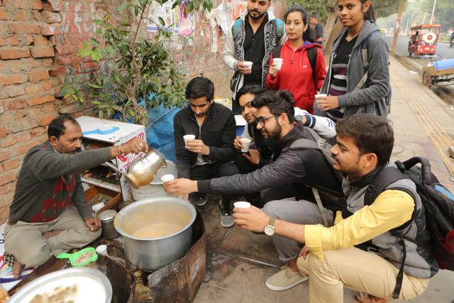 Sudama uncle pours his special tea in glasses held by students, at his stall. (Manoj Verma/HT Photo)