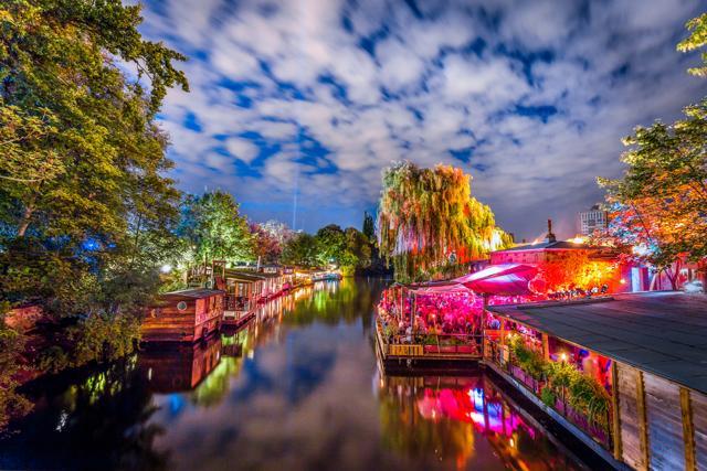 Panoramic view of young people partying in an open-air outdoor club at Flutgraben water canal in Berlin. (Shutterstock ) Panoramic view of young people partying in an open-air outdoor club at Flutgraben water canal in Berlin. (Shutterstock )
