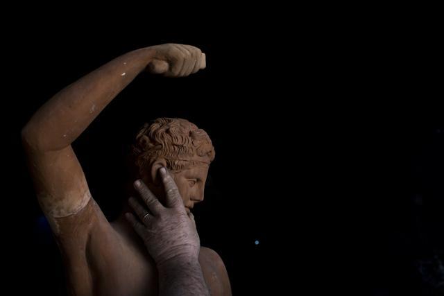 Goumas touches a terracotta statue of Hermes, messenger of the ancient Greek gods, at his workshop. (AP) Goumas touches a terracotta statue of Hermes, messenger of the ancient Greek gods, at his workshop. (AP)