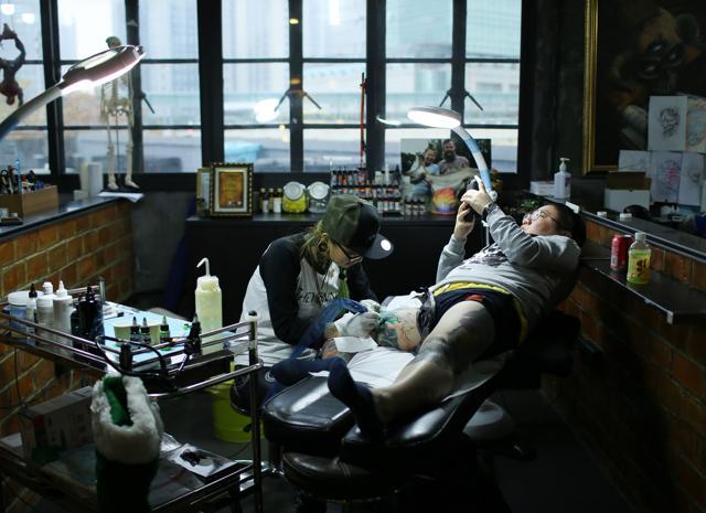 Zhuo works on Wang Qi, a web designer and tattoo enthusiast, at her studio in Shanghai. (AFP)