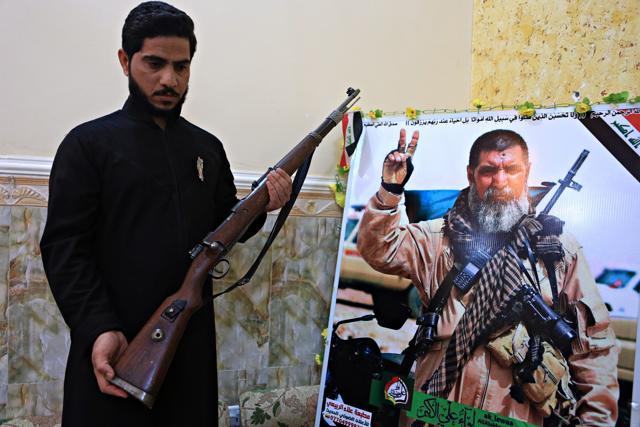 In this December 5, 2017 photo, Talib, the son of Iraqi sniper Ali Jayad al-Salhi, 65, a volunteer with Popular Mobilization Forces killed fighting Islamic State militants, poses with a weapon next to his father's poster in his home in Basra, Iraq. (AP) In this December 5, 2017 photo, Talib, the son of Iraqi sniper Ali Jayad al-Salhi, 65, a volunteer with Popular Mobilization Forces killed fighting Islamic State militants, poses with a weapon next to his father's poster in his home in Basra, Iraq. (AP)