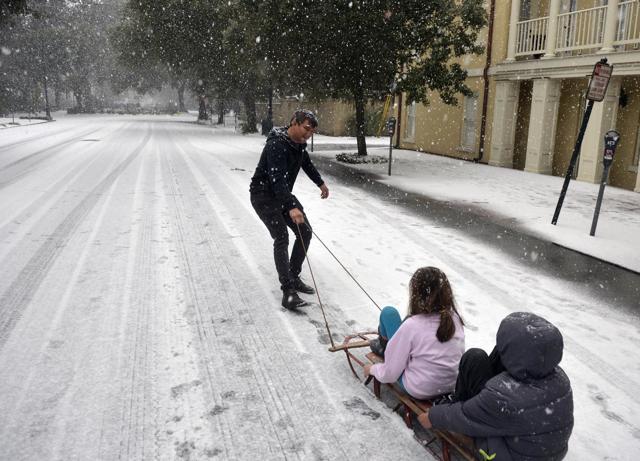 A man takes advantage of little car traffic to pull his children in a sleigh down Bull Street in Savannah, Georgia city, on January 3, 2018. Snow started falling late on Wednesday morning shutting down the city. (AP) A man takes advantage of little car traffic to pull his children in a sleigh down Bull Street in Savannah, Georgia city, on January 3, 2018. Snow started falling late on Wednesday morning shutting down the city. (AP)