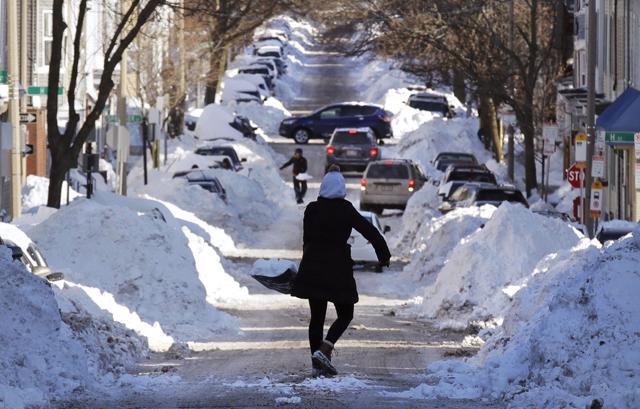 Mollie Lane carries a shovel-full of snow down the street to a pile while digging her car out in the South Boston neighborhood of Boston, Friday, Jan. 5, 2018. (AP) Mollie Lane carries a shovel-full of snow down the street to a pile while digging her car out in the South Boston neighborhood of Boston, Friday, Jan. 5, 2018. (AP)