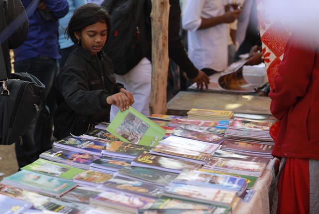 A girl flips through a book at one of the many stalls in Bhima Koregaon. Scores of shops sell anti-caste literature in pocket-sized books, often in Marathi. (Rahul Raut/HT Photo) A girl flips through a book at one of the many stalls in Bhima Koregaon. Scores of shops sell anti-caste literature in pocket-sized books, often in Marathi. (Rahul Raut/HT Photo)