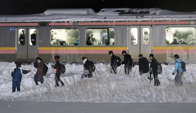 Passengers of a stranded train walk beside a railway track in Sanjo, Niigata prefecture, north of Tokyo early on Friday. (AP) Passengers of a stranded train walk beside a railway track in Sanjo, Niigata prefecture, north of Tokyo early on Friday. (AP)