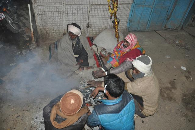 People huddle around a bonfire, which is in its dying state. (Rajesh Kumar/HT Photo)