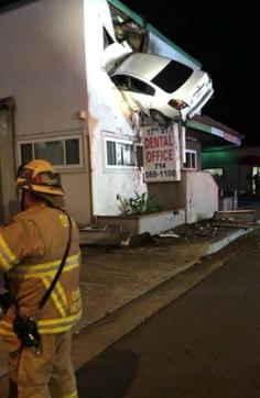 Rescue workers outside the dental office. The rear of the car was dangling from the building’s second storey after the crash. (OCFA PIO via REUTERS) Rescue workers outside the dental office. The rear of the car was dangling from the building’s second storey after the crash. (OCFA PIO via REUTERS)