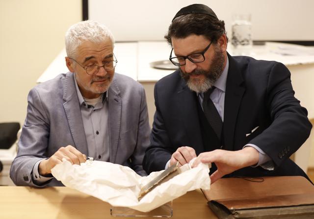 Daniel E. Kestenbaum, right, president of New York based auction house, hands over the book titled "Mikne Avram - Peculium Abrae" to director of Prague's Jewish Museum Leo Pavlat, left, in Prague, Czech Republic. (AP/Petr David Josek)