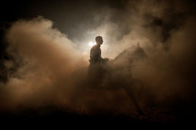 A man rides a horse through smoke in the village of San Bartolome de Pinares, northwest of Madrid, Spain. (Reuters)