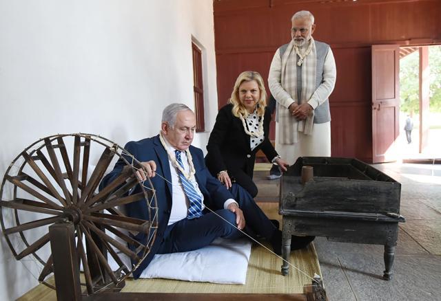 Prime Minister Narendra Modi (R), Israeli Prime Minister Benjamin Netanyahu (L) and his wife Sara Natanyahu use a spinning wheel during a visit to the Sabarmati Ashram in Ahmedabad. (AFP/ PIB) Prime Minister Narendra Modi (R), Israeli Prime Minister Benjamin Netanyahu (L) and his wife Sara Natanyahu use a spinning wheel during a visit to the Sabarmati Ashram in Ahmedabad. (AFP/ PIB)