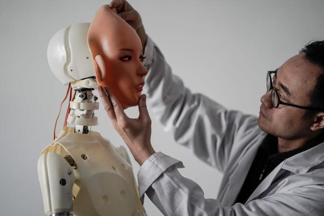 An engineer holding a silicon face against the head of a robot at a lab of a doll factory. (AFP Photo) An engineer holding a silicon face against the head of a robot at a lab of a doll factory. (AFP Photo)