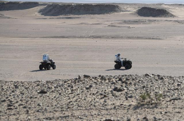 Members of the AMADEE-18 Mars simulation mission ride all-terrain vehicles while wearing spacesuits during an analog field simulation in Oman's Dhofar desert on February 7. (AFP Photo)