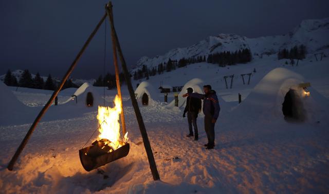 Omar Kanteh, of Gambia, left, stands next to a fire with Davide Midali, owner and manager of the igloo village. (AP) Omar Kanteh, of Gambia, left, stands next to a fire with Davide Midali, owner and manager of the igloo village. (AP)