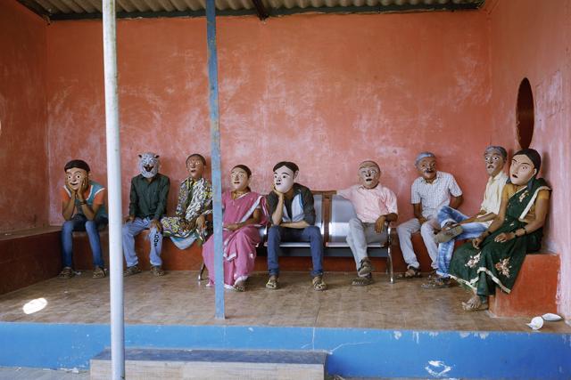 A cat waits amongst humans at a bus stop. Ordinary reality turns into the comically absurd, with the simple use of masks. (Untitled, from Acts Of Appearance, Gauri Gill)