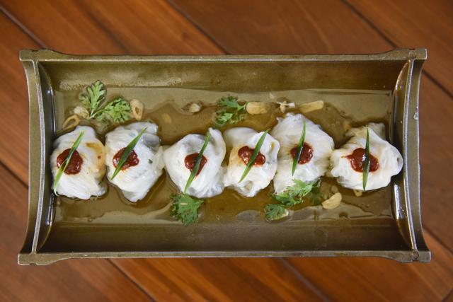 Encased in a gossamer-thin skin, the steamed sa khoo prawn and chive dumplings, topped with a mildly spicy chilli bean sauce and finely sliced garlic, are light and airy as promised. (Aalok Soni/HT Photo)